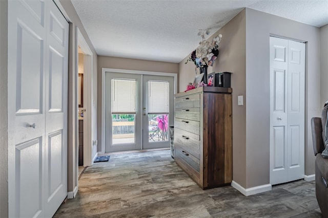 hallway with hardwood / wood-style floors, french doors, and a textured ceiling