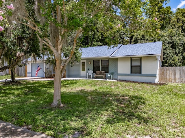 ranch-style home featuring stucco siding, a shingled roof, fence, a garage, and a front lawn