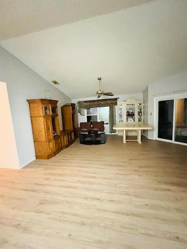 interior space featuring a textured ceiling, ceiling fan, light hardwood / wood-style floors, and vaulted ceiling