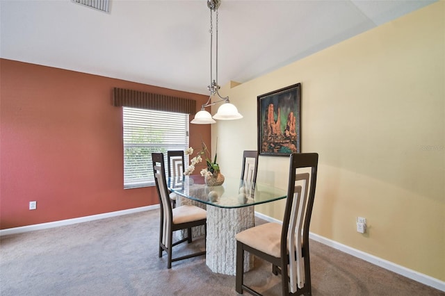 carpeted dining area featuring vaulted ceiling