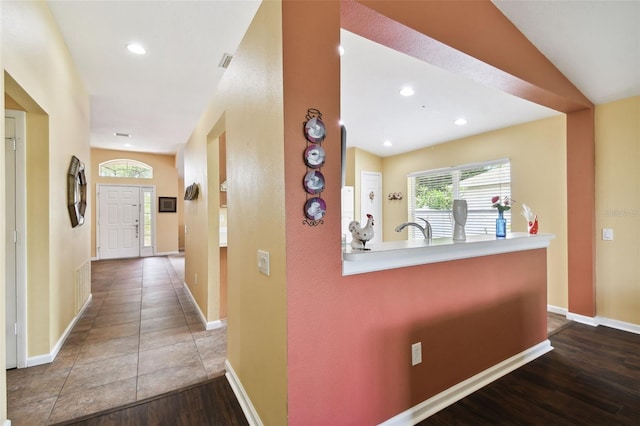 hall with sink, lofted ceiling, and hardwood / wood-style floors