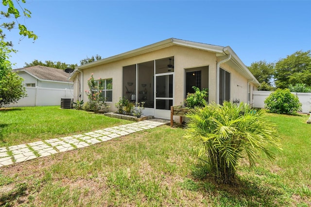 back of property with central AC, a sunroom, and a yard