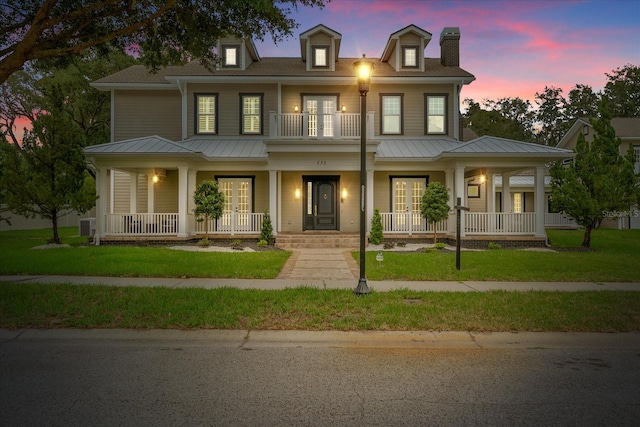 638 Limona Woods Dr, Brandon, FL 33510 - view of front of house featuring a balcony, metal roof, a front lawn, french doors, and a porch