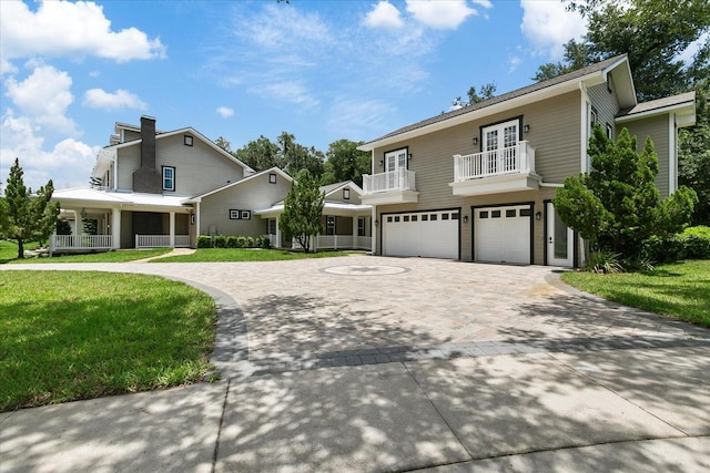 front of property with a garage, a front lawn, and a balcony