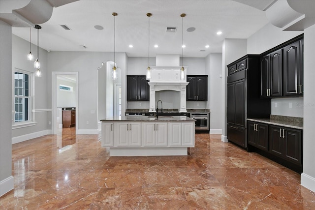 kitchen with custom range hood, tile floors, an island with sink, stainless steel oven, and pendant lighting