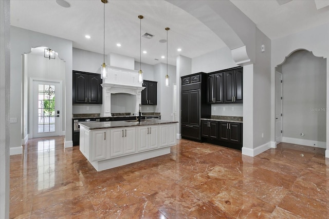 kitchen with custom range hood, a center island with sink, tile floors, a high ceiling, and pendant lighting