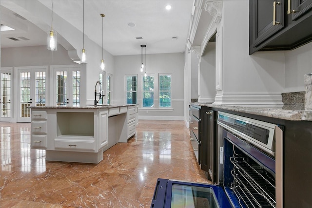 kitchen featuring sink, light stone counters, and white cabinetry