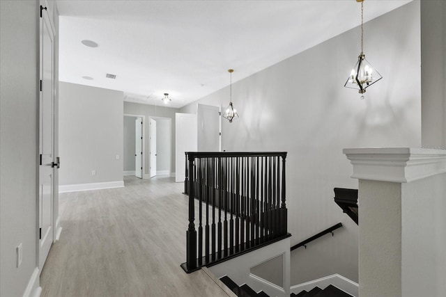 hallway with light hardwood / wood-style floors and a chandelier