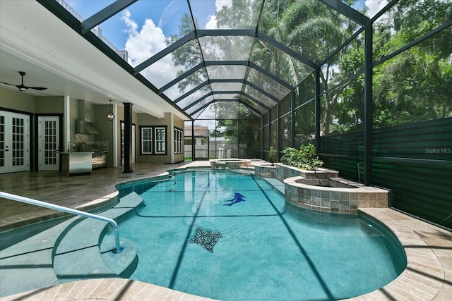 view of pool featuring glass enclosure, an in ground hot tub, ceiling fan, a patio, and french doors