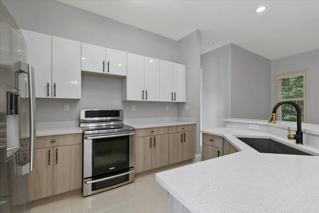 kitchen featuring double oven range, light tile flooring, light brown cabinetry, sink, and white cabinetry