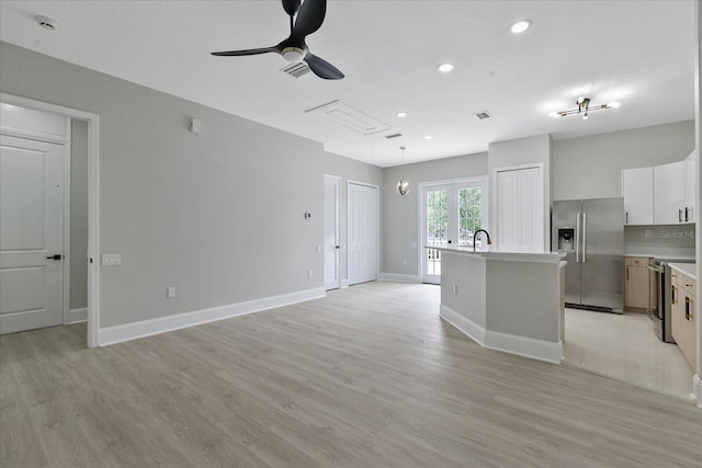 kitchen with stainless steel fridge with ice dispenser, light wood-type flooring, a center island with sink, and pendant lighting