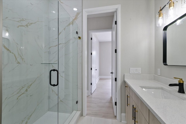 bathroom with a shower with door, hardwood / wood-style flooring, and oversized vanity