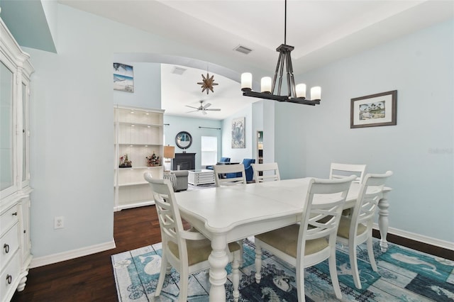 dining room featuring ceiling fan with notable chandelier and dark wood-type flooring