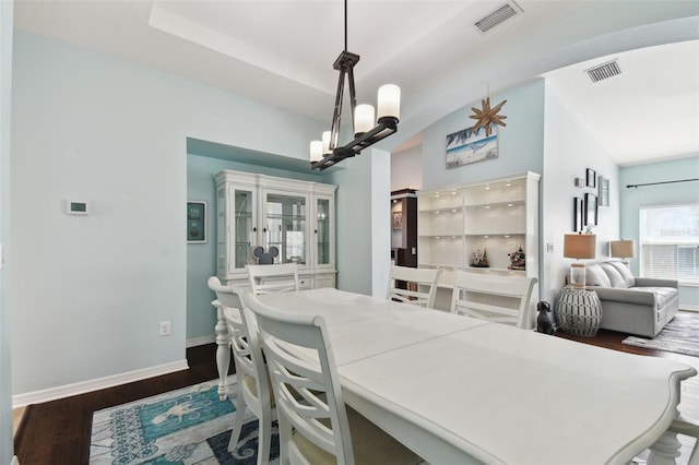 dining room with lofted ceiling, dark hardwood / wood-style flooring, and a chandelier