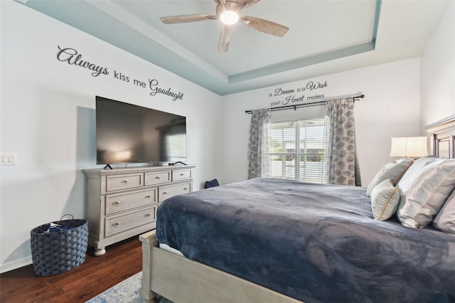 bedroom featuring dark wood-type flooring, ceiling fan, and a tray ceiling