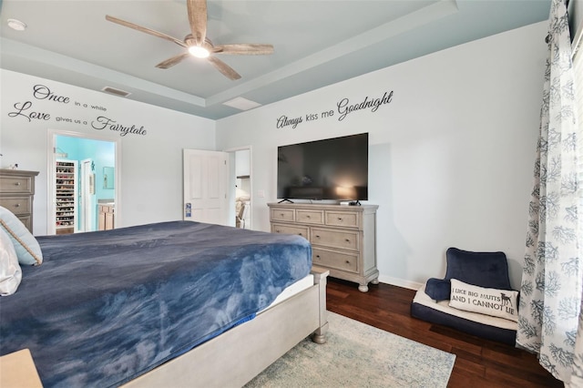 bedroom featuring a raised ceiling, dark hardwood / wood-style floors, connected bathroom, and ceiling fan