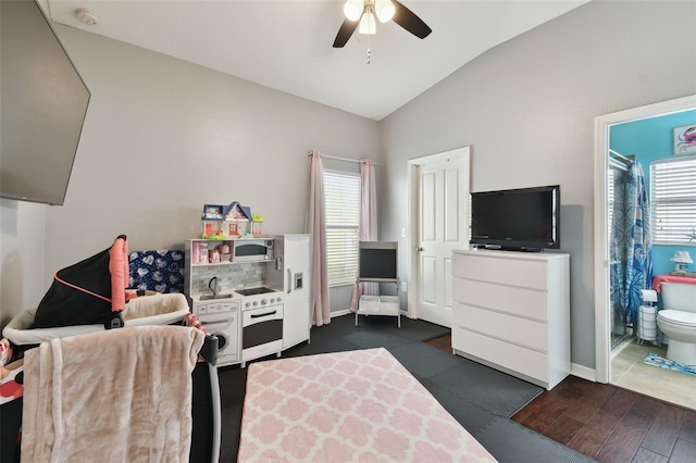 bedroom featuring ceiling fan, ensuite bath, vaulted ceiling, and multiple windows