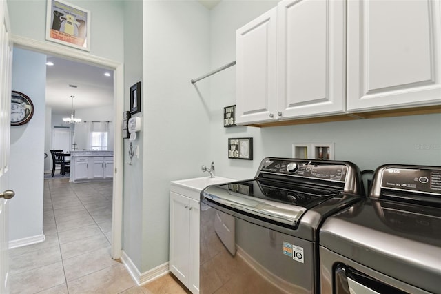 clothes washing area with sink, cabinets, a chandelier, light tile patterned floors, and independent washer and dryer