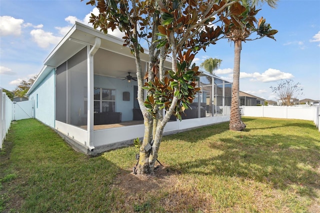 rear view of property featuring a yard, ceiling fan, and glass enclosure