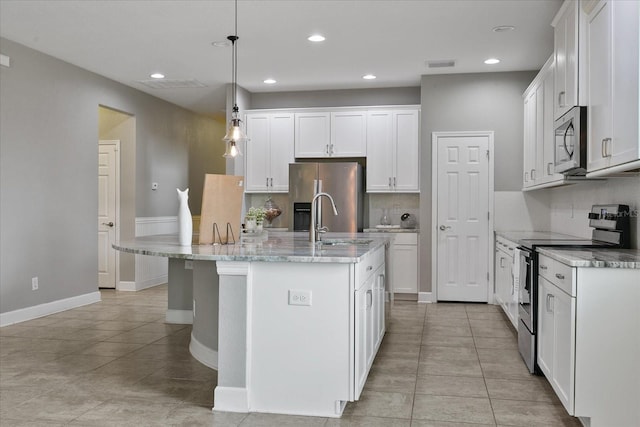 kitchen with a center island with sink, white cabinets, hanging light fixtures, and appliances with stainless steel finishes