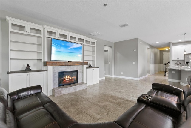 living room featuring built in shelves, a fireplace, and a textured ceiling