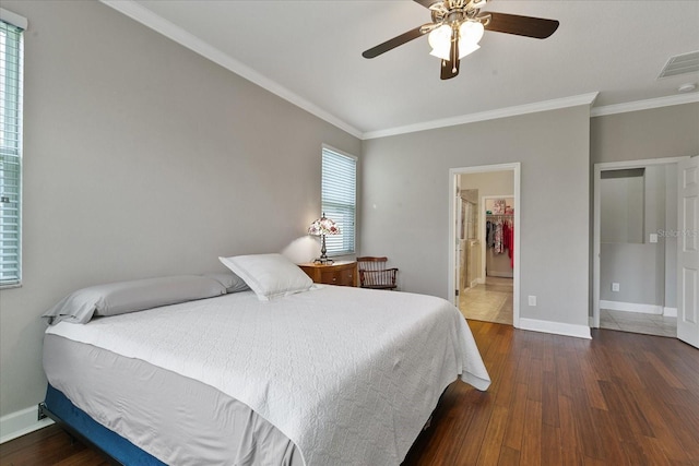 bedroom with a walk in closet, dark hardwood / wood-style flooring, ceiling fan, and crown molding