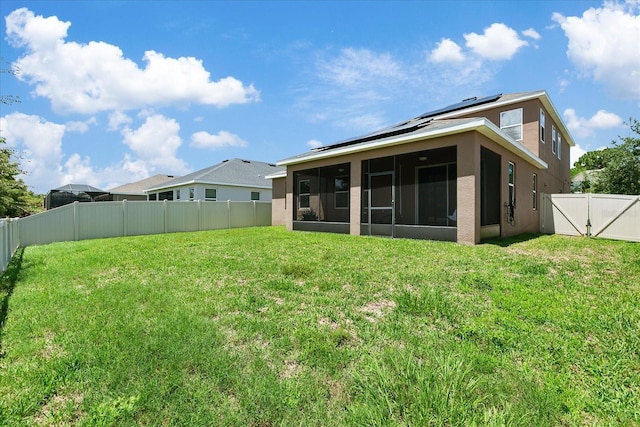 rear view of property with a sunroom, solar panels, and a lawn