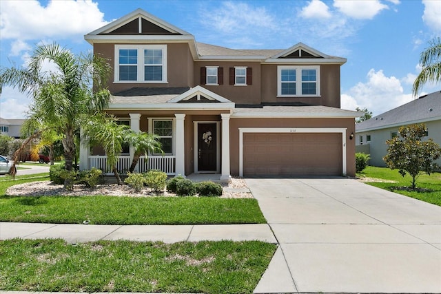 view of front of house featuring covered porch, a garage, and a front lawn