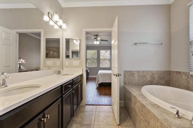 bathroom featuring tile patterned floors, ornamental molding, vanity, ceiling fan, and a relaxing tiled tub