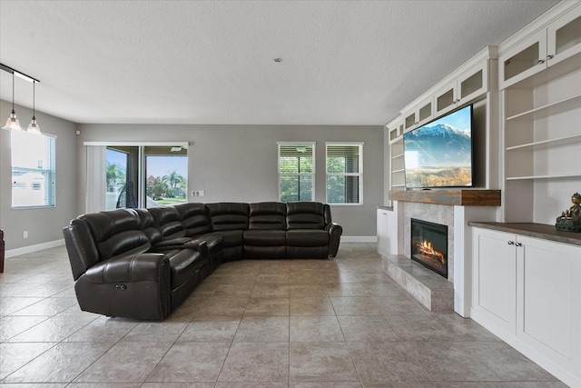 living room featuring built in features, a textured ceiling, and a tile fireplace