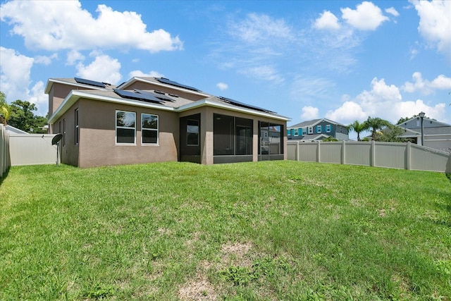 back of property featuring solar panels, a yard, and a sunroom