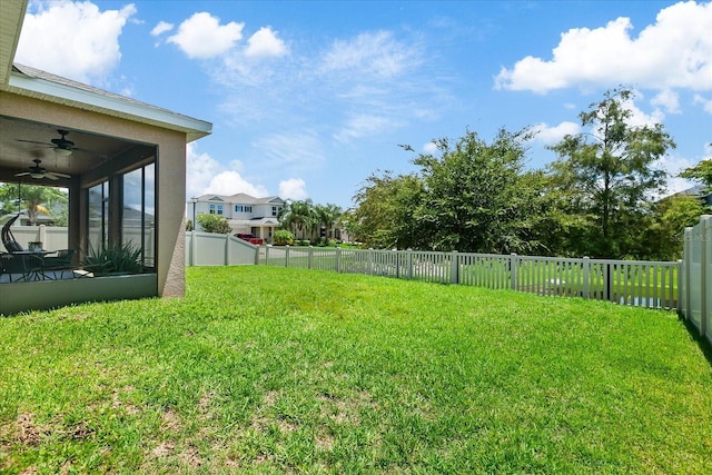 view of yard featuring a sunroom and ceiling fan