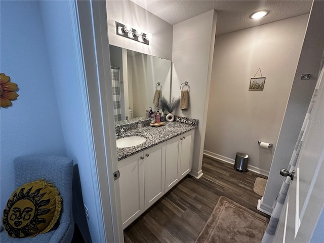 bathroom with a textured ceiling, vanity, and wood-type flooring