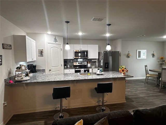 kitchen featuring hanging light fixtures, white cabinetry, appliances with stainless steel finishes, and kitchen peninsula