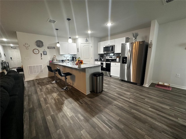 kitchen with appliances with stainless steel finishes, white cabinetry, kitchen peninsula, and dark wood-type flooring