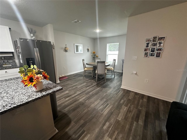 kitchen with dark stone counters, white cabinets, stainless steel fridge with ice dispenser, and dark wood-type flooring