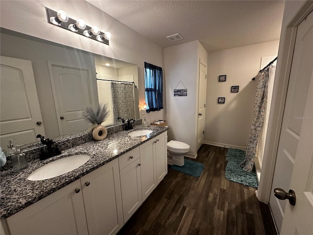 full bathroom with shower / tub combo, dual vanity, a textured ceiling, toilet, and wood-type flooring