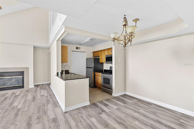 kitchen with kitchen peninsula, sink, an inviting chandelier, light hardwood / wood-style flooring, and stainless steel appliances