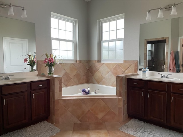 bathroom featuring tile patterned flooring, vanity, and a relaxing tiled tub