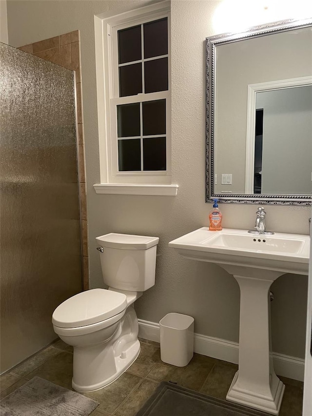 bathroom with a shower with door, tile patterned flooring, and toilet