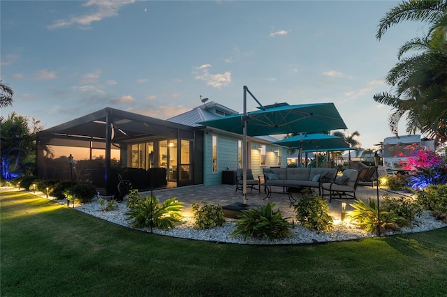 back house at dusk featuring outdoor lounge area, a yard, a lanai, and a patio area