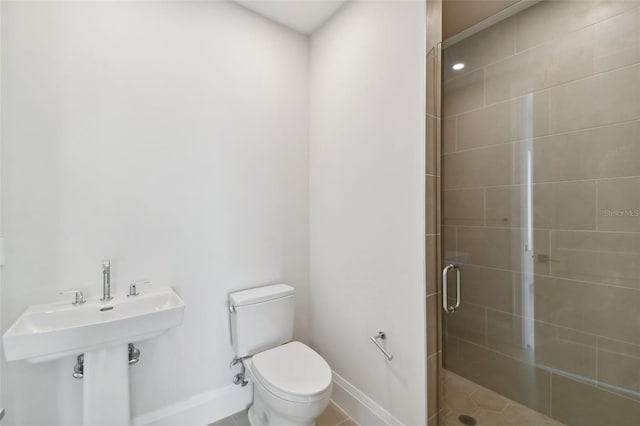 bathroom featuring tile patterned flooring, toilet, and a shower with shower door