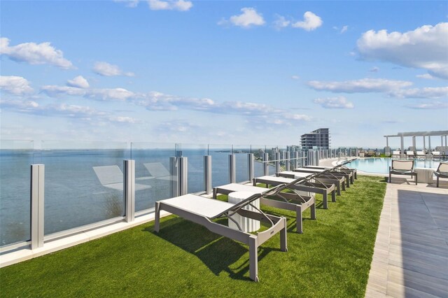 exterior space featuring a water view, a community pool, and a lawn