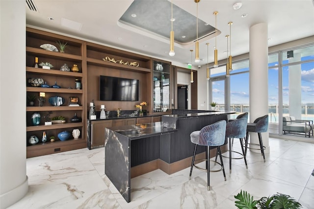 bar with a raised ceiling, built in shelves, sink, and hanging light fixtures