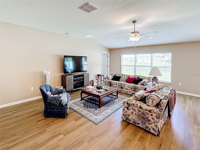 living room with vaulted ceiling, ceiling fan, a textured ceiling, and hardwood / wood-style flooring