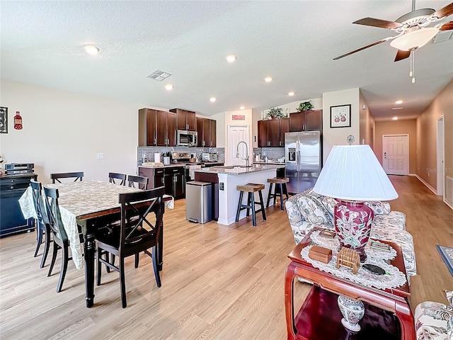 dining room featuring ceiling fan, sink, a textured ceiling, and light hardwood / wood-style flooring