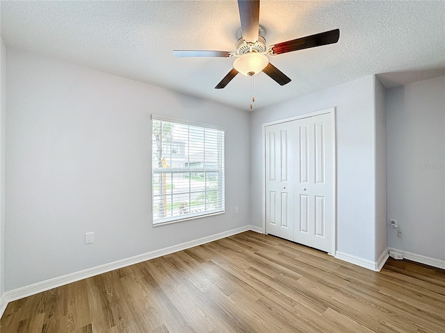 unfurnished bedroom featuring ceiling fan, a closet, a textured ceiling, and light wood-type flooring