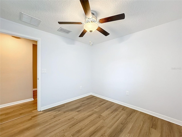 empty room with ceiling fan, light hardwood / wood-style flooring, and a textured ceiling