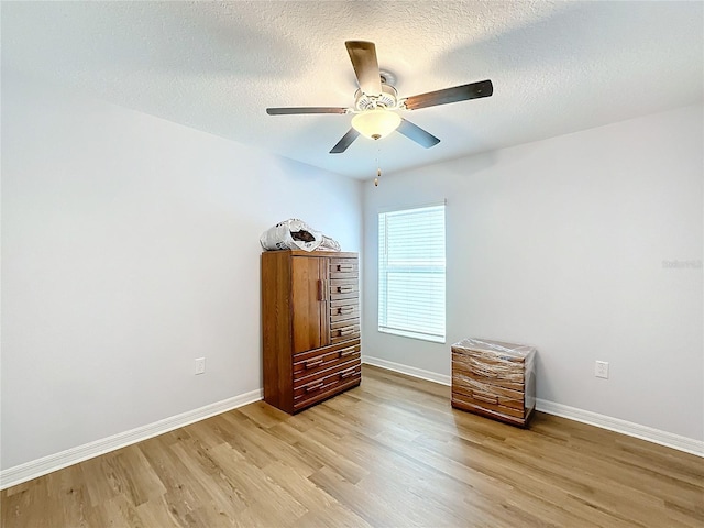 bedroom featuring ceiling fan, light hardwood / wood-style flooring, and a textured ceiling