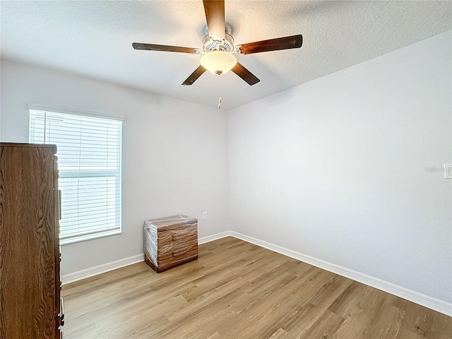 unfurnished room with ceiling fan, light hardwood / wood-style flooring, and a textured ceiling